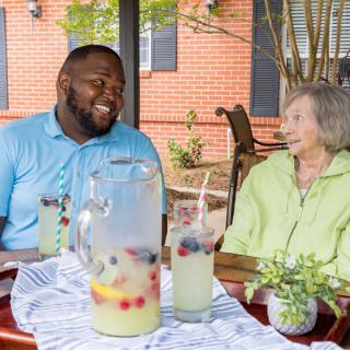 Two people enjoying a conversation over lemonade in an outdoor setting.