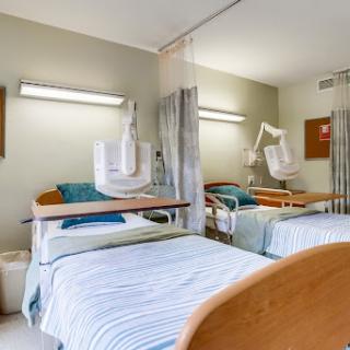 A view of a hospital patient room featuring two beds and medical equipment.