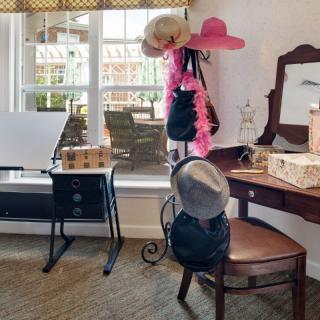 A charming vintage-style room with a vanity table adorned with hats and decorative items.