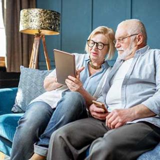 Elderly couple using a tablet together in the living room.