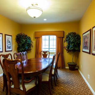 A cozy dining room with a wooden table and chairs, decorated with wall art and indoor plants.