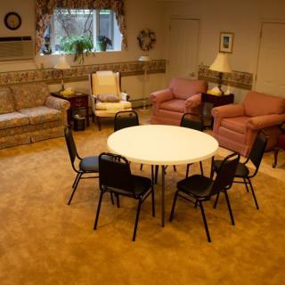 A cozy living room with a round table surrounded by various chairs and sofas.