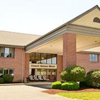 The entrance of a brick hotel with well-maintained landscaping.