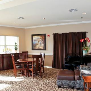 A cozy living room featuring a wooden table, chairs, artwork, and a piano.