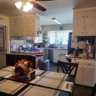 A cozy kitchen with a dining area, featuring white cabinets, a ceiling fan, and various appliances.