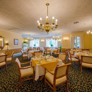 An elegant dining area with chandeliers and neatly arranged tables and chairs.
