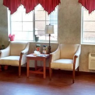 A cozy waiting room with chairs, a table, and a lamp by the windows.