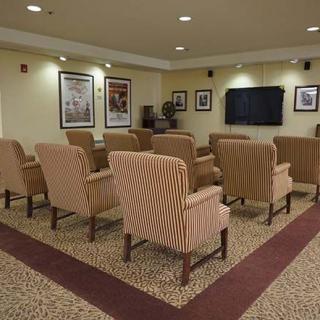 A cozy theater room with rows of comfortable chairs facing a large screen, decorated with framed posters on the walls.