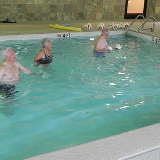 A group of people exercising in an indoor swimming pool.