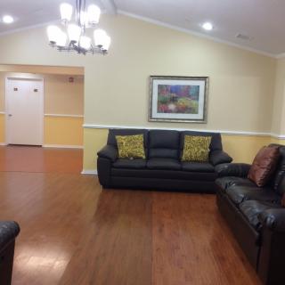 A cozy living room with leather sofas, a chandelier, and wooden flooring.