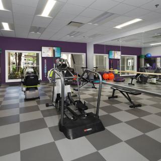 A well-equipped gym with various exercise machines and mirrored walls.