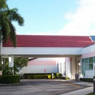 A building with a red-tiled roof and palm tree in the foreground.