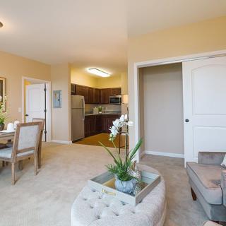 A modern apartment with an open-plan design, featuring a cozy living room, adjacent dining area, and a compact kitchen.