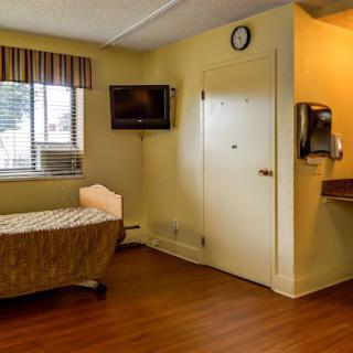 A well-lit hospital room with a bed, television, and sink.