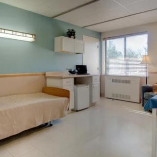 A clean and organized hospital room with a patient bed near a window.