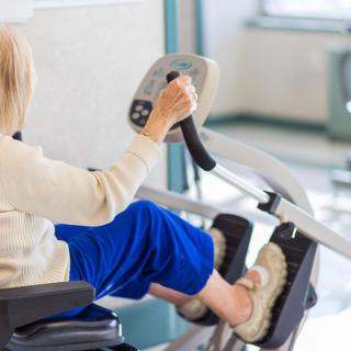An elderly person using an exercise machine indoors for physical therapy.