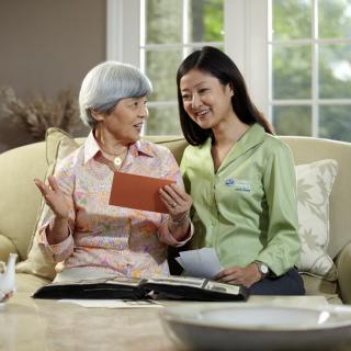 A young woman and an elderly woman sitting on a couch, engaged in conversation and sharing a moment together.