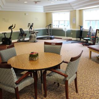 A fitness room with exercise equipment and a seating area.