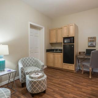 A cozy living area with chairs, a small kitchenette, and a work desk.