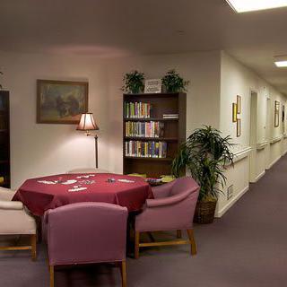 A cozy reading nook with a round table and chairs, surrounded by bookshelves in a quiet corridor.
