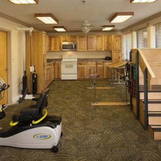 A rehabilitation space with exercise equipment and a kitchen area for therapy activities.