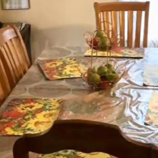 A dining table set with colorful placemats and a centerpiece fruit basket.