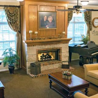 A cozy living room with a fireplace, piano, and comfortable seating area.