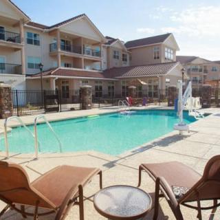 A sunny day at a residential apartment complex featuring an outdoor swimming pool and lounge chairs.