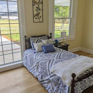 A cozy bedroom with a single bed and a large window letting in natural light.