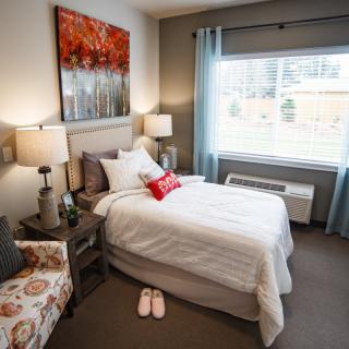 A cozy bedroom with a neatly made bed, decorated with soft lighting and warm colors.
