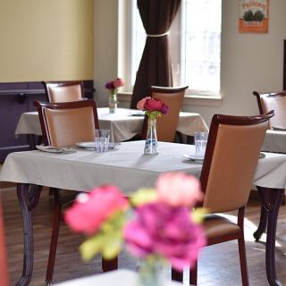 Elegant restaurant interior with tables set for dining, featuring fresh flowers as centerpieces.