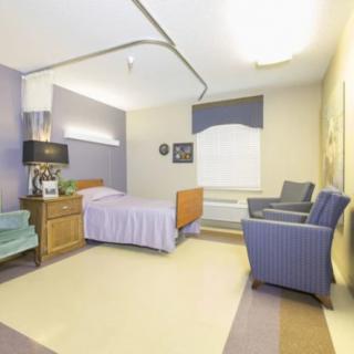 A neatly organized hospital room with a bed, chairs, and a large window.