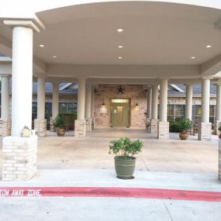 A welcoming entrance featuring elegant architecture with pillars and potted plants.