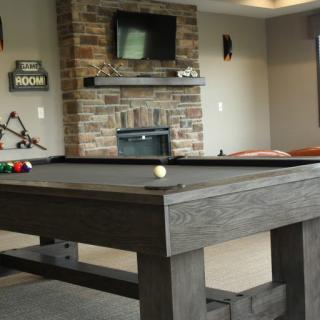 A stylish recreation room featuring a pool table, fireplace, and wall-mounted television.