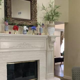 A beautifully decorated fireplace with a mirror and vases of flowers.