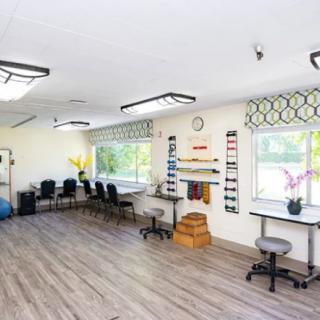 A bright rehabilitation room equipped with chairs and therapy tools.