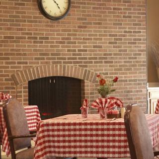 Cozy restaurant interior with checkered tablecloths and a brick fireplace.