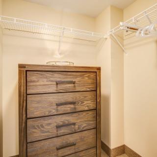 A closet featuring a wooden dresser and wire shelving for storage.