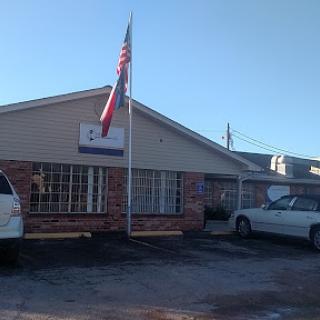 A commercial building displaying the American flag with parked vehicles in front.