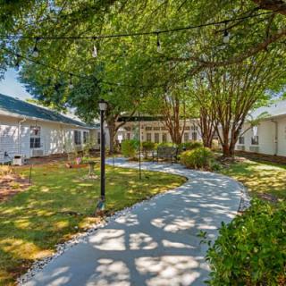 A peaceful garden with a winding pathway under the shade of tall trees.