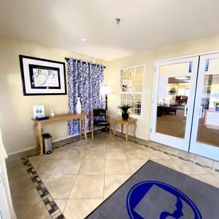 A bright and welcoming lobby entrance with decorative elements, a console table, and double doors leading to another room.