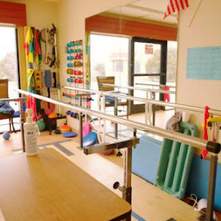 A well-equipped physical therapy room featuring parallel bars and various exercise tools.