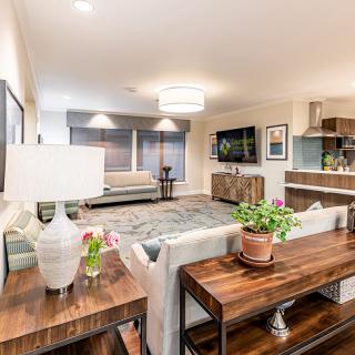 A modern living room with stylish furniture and decor, featuring a comfortable sofa, a wooden coffee table, decorative plants, and a wall-mounted television.