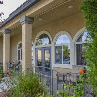 A view of a building entrance featuring arched windows, columns, and surrounding greenery.