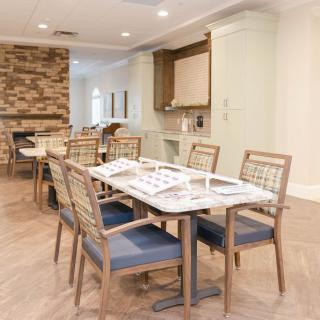 A modern dining area with neatly arranged tables and chairs, featuring light-colored walls and a stone accent wall.