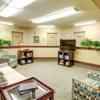 A comfortable waiting room with seating, a television, and decorative plants.