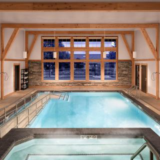 Luxurious indoor spa with large windows and wooden beam architecture.