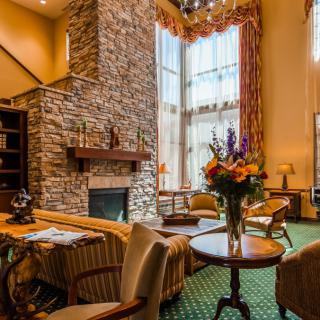 A cozy living room with a stone fireplace, large windows, and elegant decor.