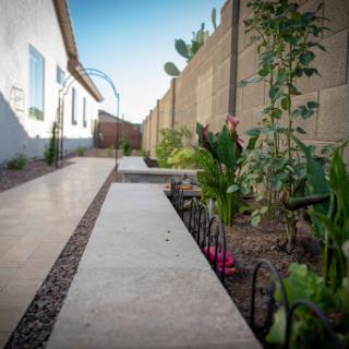 A serene garden pathway lined with vibrant flowers and plants, leading towards the home.