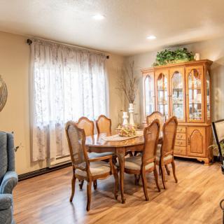 A cozy dining room with a wooden table, chairs, and a display cabinet.